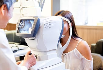 Optometrist giving a young woman an eye exam for ACUVUE contact lenses fitting, Singapore